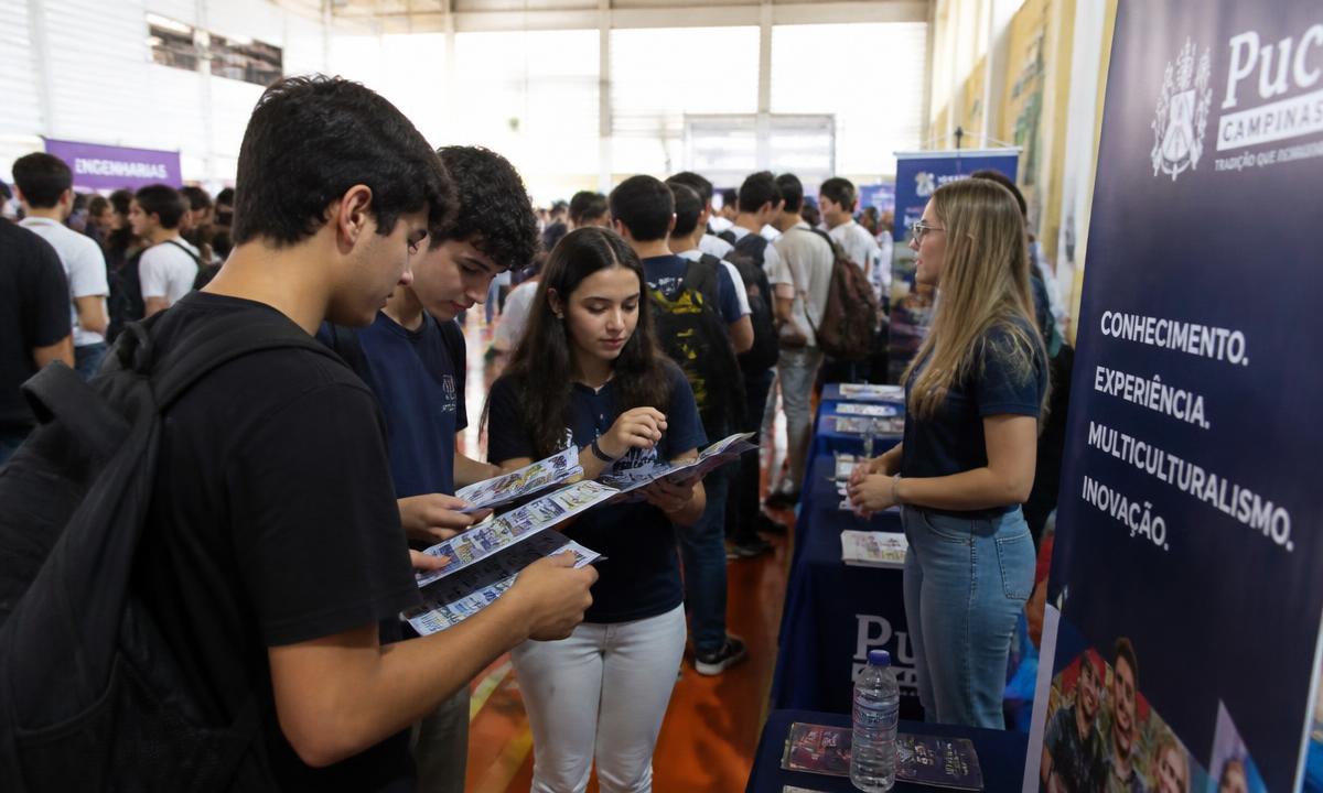 Estudantes em feira de profissões olhando folhetos de universidades